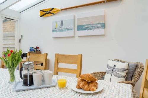 a table with a plate of croissants and orange juice at Firefly House in Cowes