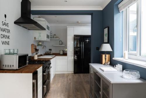 cocina con paredes azules, armarios blancos y encimera en Fitzroy, en Cowes