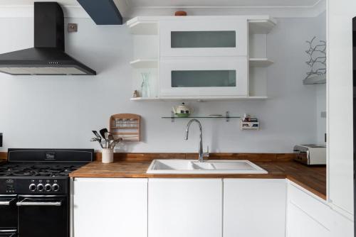 a kitchen with white cabinets and a sink at Fitzroy in Cowes