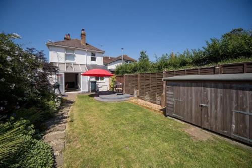 a backyard with a fence and a red umbrella at Skysail, Gurnard in Gurnard