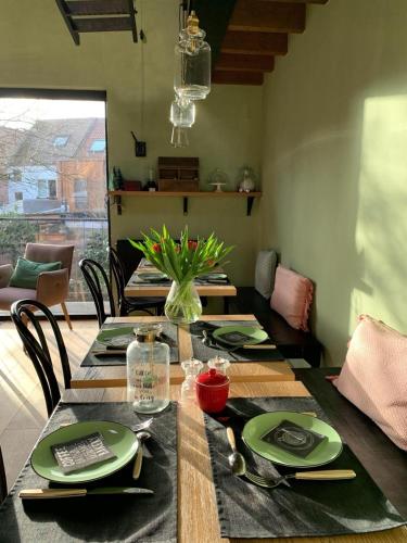 a dining room table with green plates and a vase of flowers at B&B PETIT PRINCE, GENT in Ghent