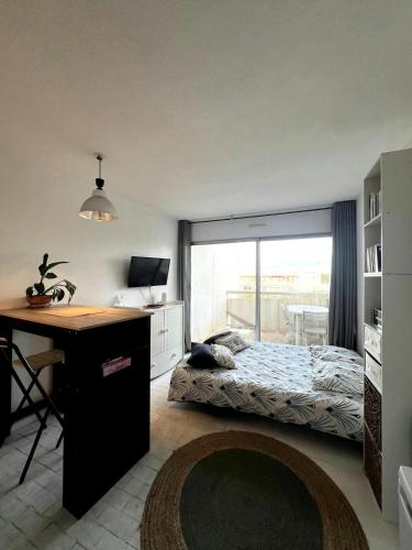 une chambre avec un lit et un bureau avec un bureau dans l'établissement Joli studio avec piscine., à La Grande Motte