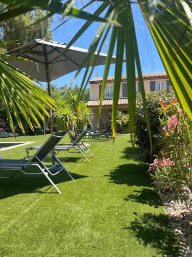 une cour avec des chaises et des palmiers ainsi qu'un bâtiment dans l'établissement Villa Largo l Pool & Beachside l Shellter Rentals, à Grimaud