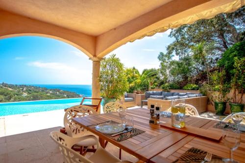 - une table et des chaises en bois sur une terrasse avec vue sur l'océan dans l'établissement Villa La Vigie l Pool & Sea l Shellter Rentals, à Ramatuelle