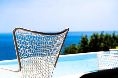 une chaise blanche assise à côté d'une piscine dans l'établissement Villa La Vigie l Pool & Sea l Shellter Rentals, à Ramatuelle