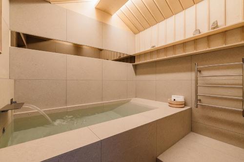 a bathroom with a tub with a shower and a sink at Luxury Hanok Stay CORED in Seoul