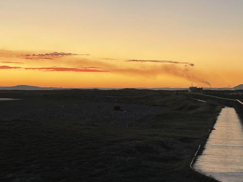 a sunset over a field with a body of water at Seafront apartment with spectacular views in Porthcawl