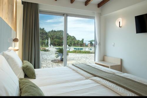 una camera da letto con un letto e una grande finestra di Villa Aurora Blue with private pool - just tens of meters from the sea - by PosarelliVillas ad Acharavi