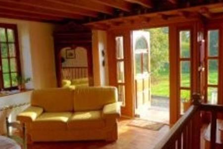 - un salon avec un canapé jaune et des portes coulissantes en verre dans l'établissement le vieux logis, à Le PARC