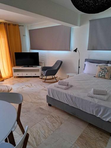 a bedroom with a bed and a tv and a chair at Modern apartment in Paleo Tsifliki
