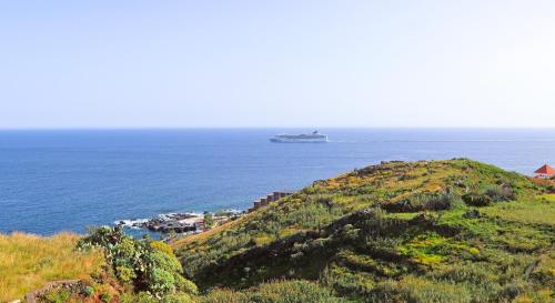 a cruise ship in the ocean next to a hill at Vista Reis Magos in Caniço