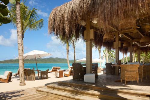 a restaurant on the beach with chairs and umbrellas at Hermitage Bay - All Inclusive in Saint Johnʼs