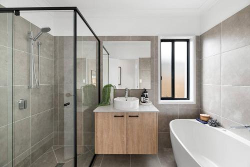 a bathroom with a tub and a sink and a shower at Noble Casa Brand New Estate Sleeps 8 Burpengary East in Morayfield