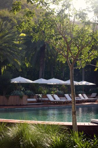 a swimming pool with lounge chairs and umbrellas at Hermitage Bay - All Inclusive in Saint Johnʼs