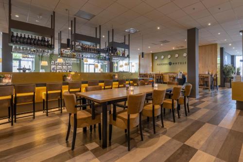 a restaurant with a wooden table and chairs at Fletcher Wellness-Hotel Sittard in Sittard