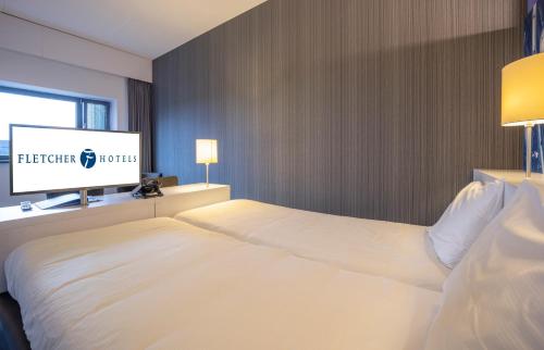 a hotel room with a bed and a flat screen tv at Fletcher Wellness-Hotel Sittard in Sittard