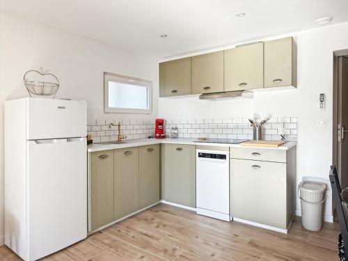 une cuisine avec des appareils électroménagers blancs et du parquet dans l'établissement Gamins des Sables - Clim - Jardin - Meublé de tourisme 3 étoiles, à La Teste-de-Buch