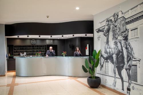 two people standing at a counter in a building with a horse mural at Hotel Marc'Aurelio in Rome