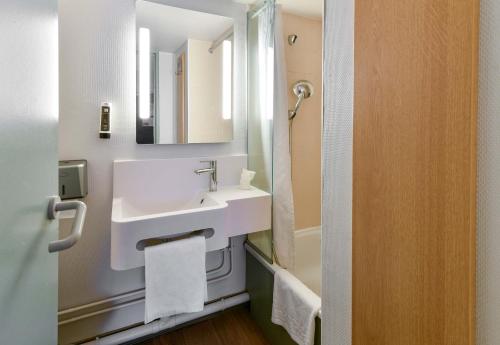 a white bathroom with a sink and a mirror at B&B HOTEL Toulouse Cité de l'Espace Mouchotte in Toulouse
