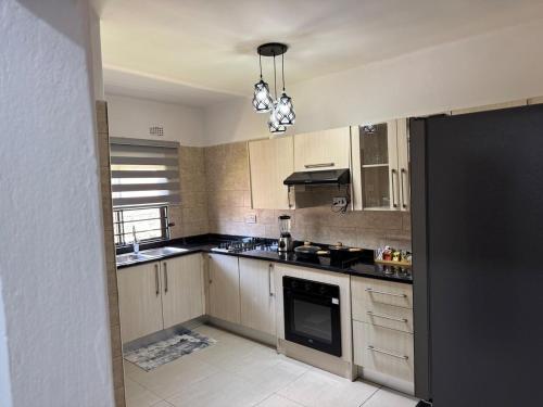 una cucina con armadi in legno e ripiani neri di Kachimam Apartment a Lusaka