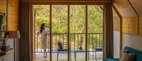 a woman standing on a porch looking out of a glass door at Perfectstayz The Silhouette in Shivpuri