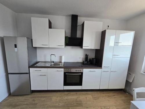 a white kitchen with white cabinets and a sink at Apartment Sonnenblick in Bohmte