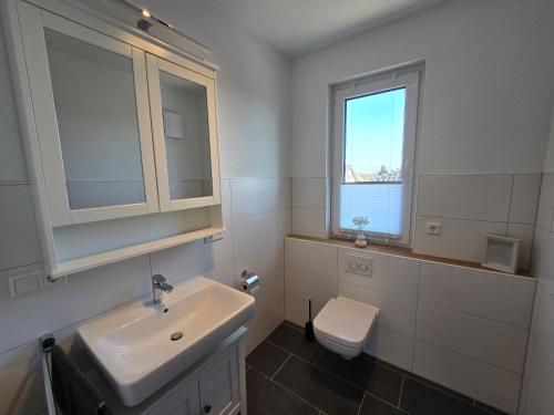 a bathroom with a sink and a toilet and a window at Apartment Sonnenblick in Bohmte