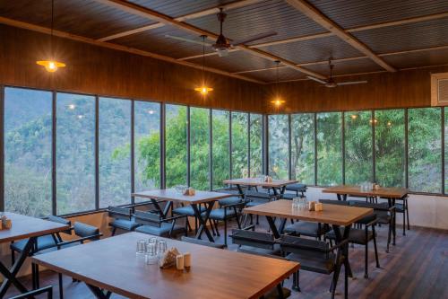 a restaurant with tables and chairs and large windows at Perfectstayz The Silhouette in Shivpuri