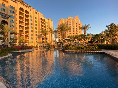 a swimming pool in a resort with palm trees and buildings at Fairmont North 2BR 2 Balconies Sea View in Dubai