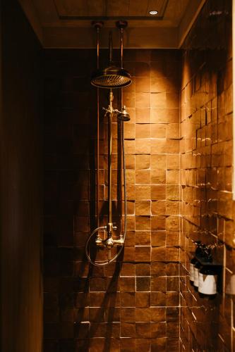 a shower in a bathroom with a brick wall at Hoel Gård - Herregården ved Mjøsa in Nes i Ådal