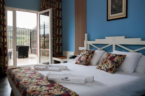 a bedroom with a large white bed with blue walls at Nuevo Hotel Parque Cabaneros in Horcajo de los Montes