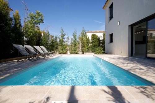 une piscine avec des chaises et une maison dans l'établissement La Villa Infinity, à Villeneuve-Loubet