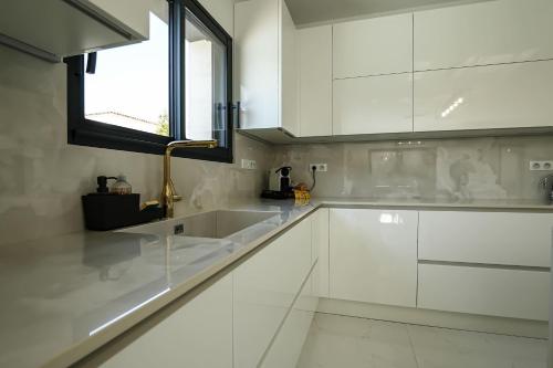 une cuisine blanche avec un évier et une fenêtre dans l'établissement La Villa Infinity, à Villeneuve-Loubet