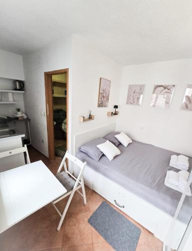 a white bedroom with a large bed and a chair at Private bedroom with bathroom in Baška Voda