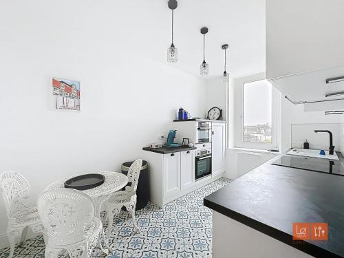 une cuisine blanche avec une table et des chaises dans l'établissement Wimereux - Appartement 2 chambres proche mer et centre, à Wimereux