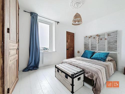 une chambre avec un lit avec des oreillers bleus et une fenêtre dans l'établissement Wimereux - Appartement 2 chambres proche mer et centre, à Wimereux