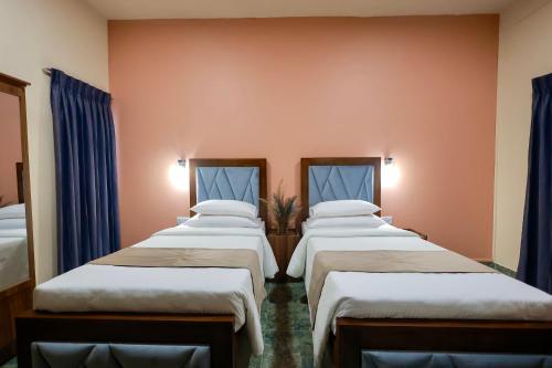 a row of four beds in a room with blue curtains at Limeshine Residence - Airport Transit Hotel in Katunayake