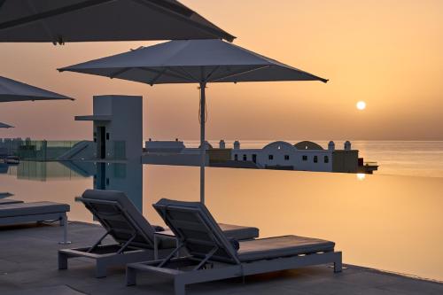 a couple of chairs and umbrellas on a pool at Lindos Grand Resort & Spa - Adults Only in Líndos