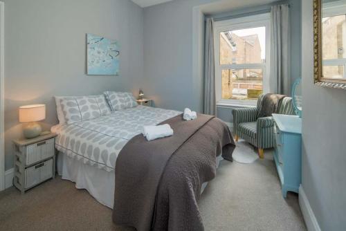 Un dormitorio con una cama, una silla y una ventana en The Seagull Apartment, en Cowes