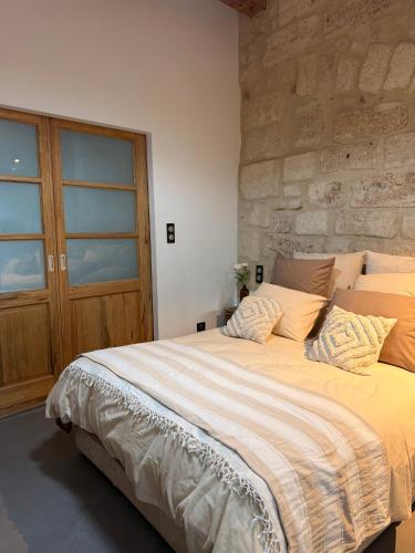 - un grand lit dans une chambre dotée d'un mur en pierre dans l'établissement Casbah14 Uzès, à Uzès