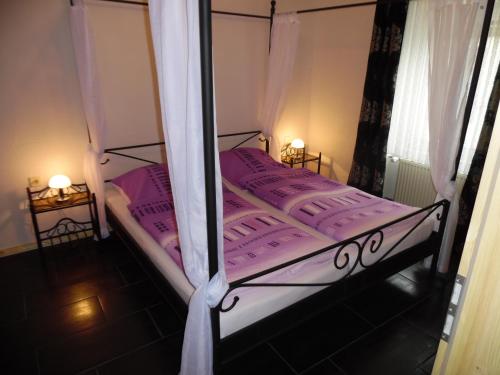 a bedroom with a bed with pink sheets and curtains at Ferienwohnung In Vino Veritas in Neumagen-Dhron