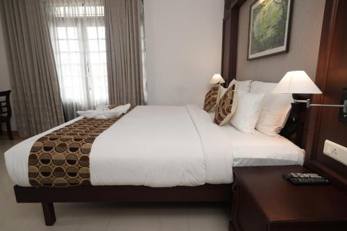 a hotel room with a large bed and a table at Rustic Leisures Resort in Cochin
