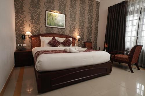 a bedroom with a large bed and a chair at Rustic Leisures Resort in Cochin