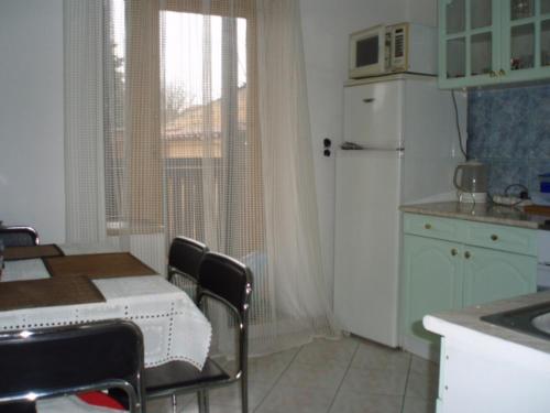 a kitchen with a table and a white refrigerator at Belvárosi Vendégház in Miskolc