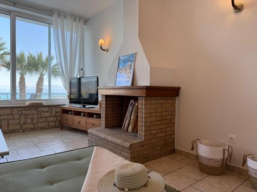 a living room with a fireplace and a television at La Vista Residence - 5 BDS, 2 private swimming pools, stunning sea views only 10 minutes from Corfu Town's Centre in Gouvia