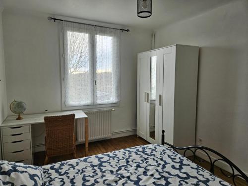 a bedroom with a bed and a desk and window at Petite maison 2 chambres Guéret in Guéret