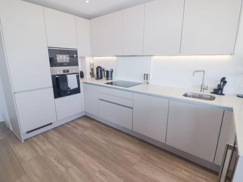 a kitchen with white cabinets and a wooden floor at Seafront apartment with spectacular views in Porthcawl