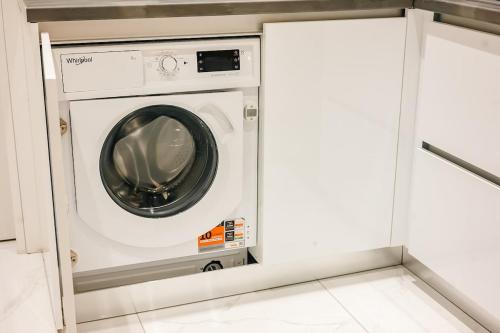 a washer and dryer in a white laundry room at Sunset luxury studio by the sea in Athens