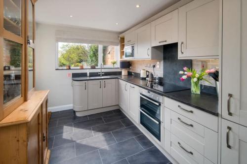 a kitchen with white cabinets and black counter tops at Lily Cottage in Gurnard