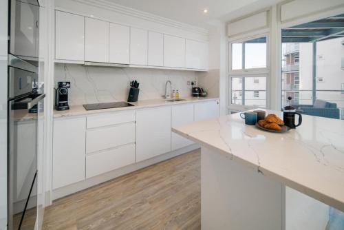 a white kitchen with white cabinets and a counter at Saltwater apartment in Cowes